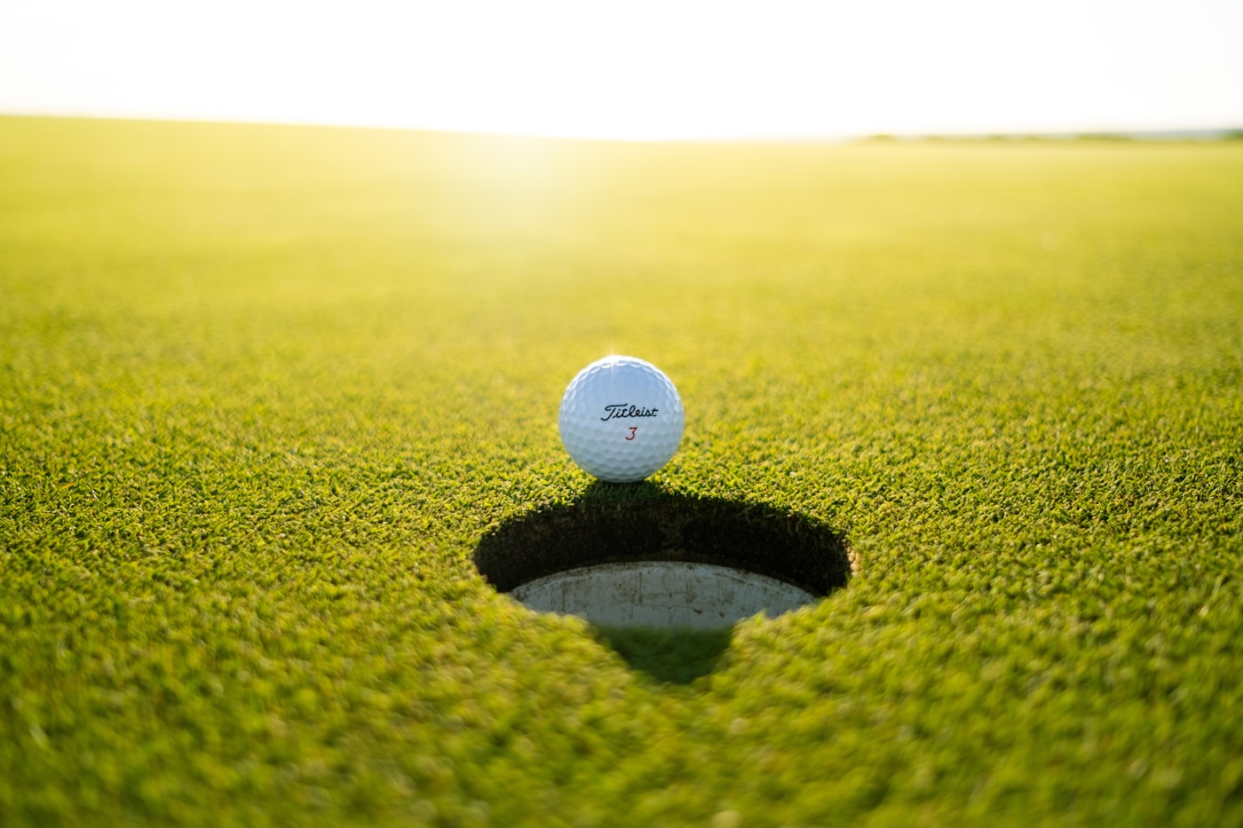 Golf ball on the lip of the cup on a green